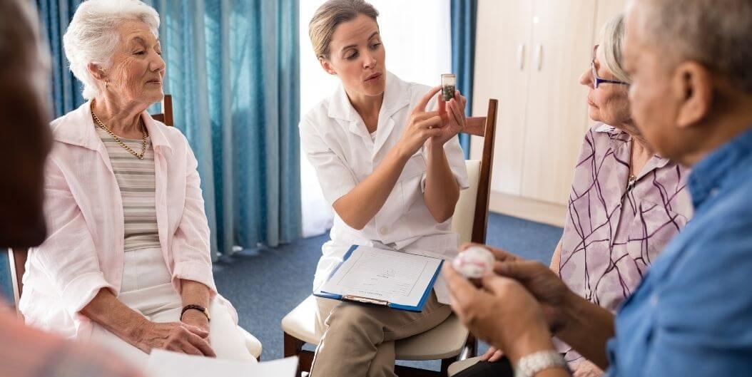 Female Nurse Administering Medication to Elderly Couple at Assisted Living Facility