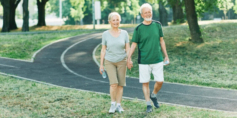 Elderly Couple Holding Hands on Walking Trail in Assisted Living